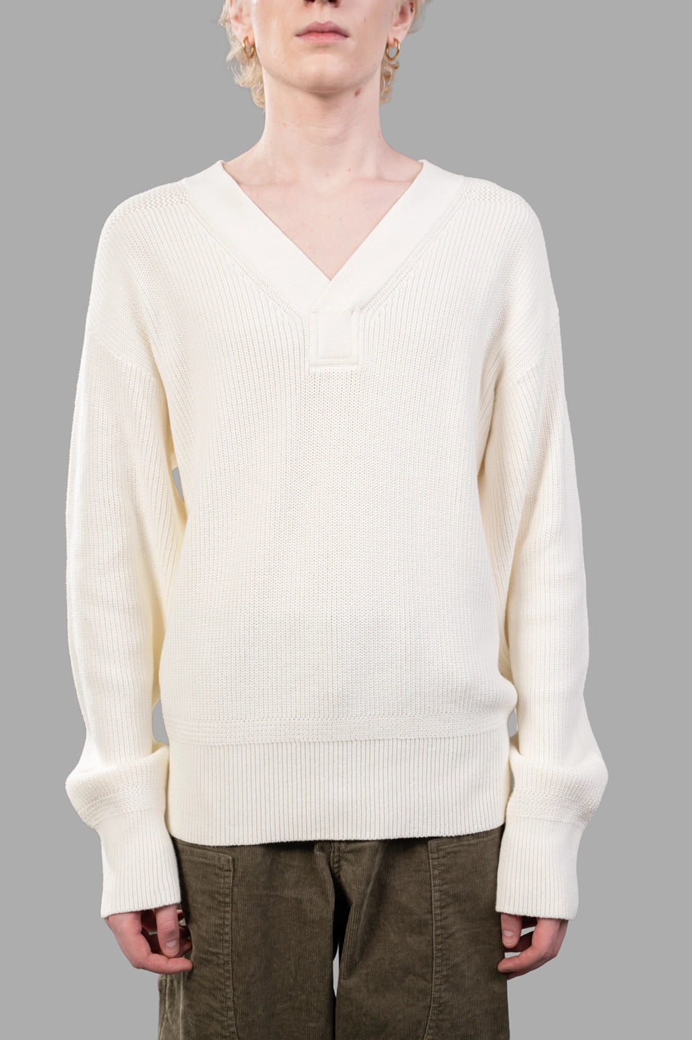 Front close-up of white ribbed V-neck sweater showing wide rib knit and V overlay