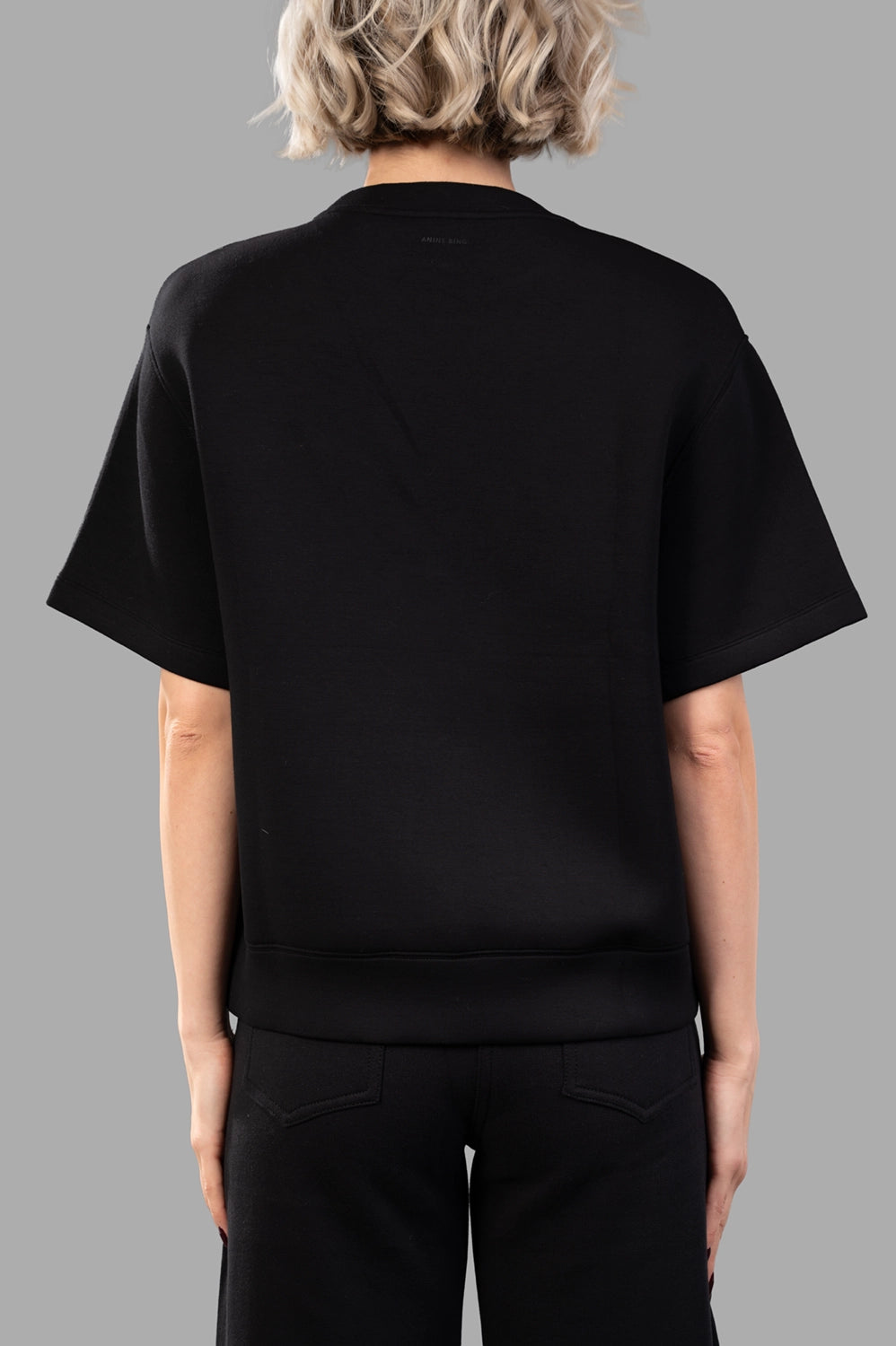 Back close-up of black short-sleeve sweatshirt with clean seams and ribbed hem