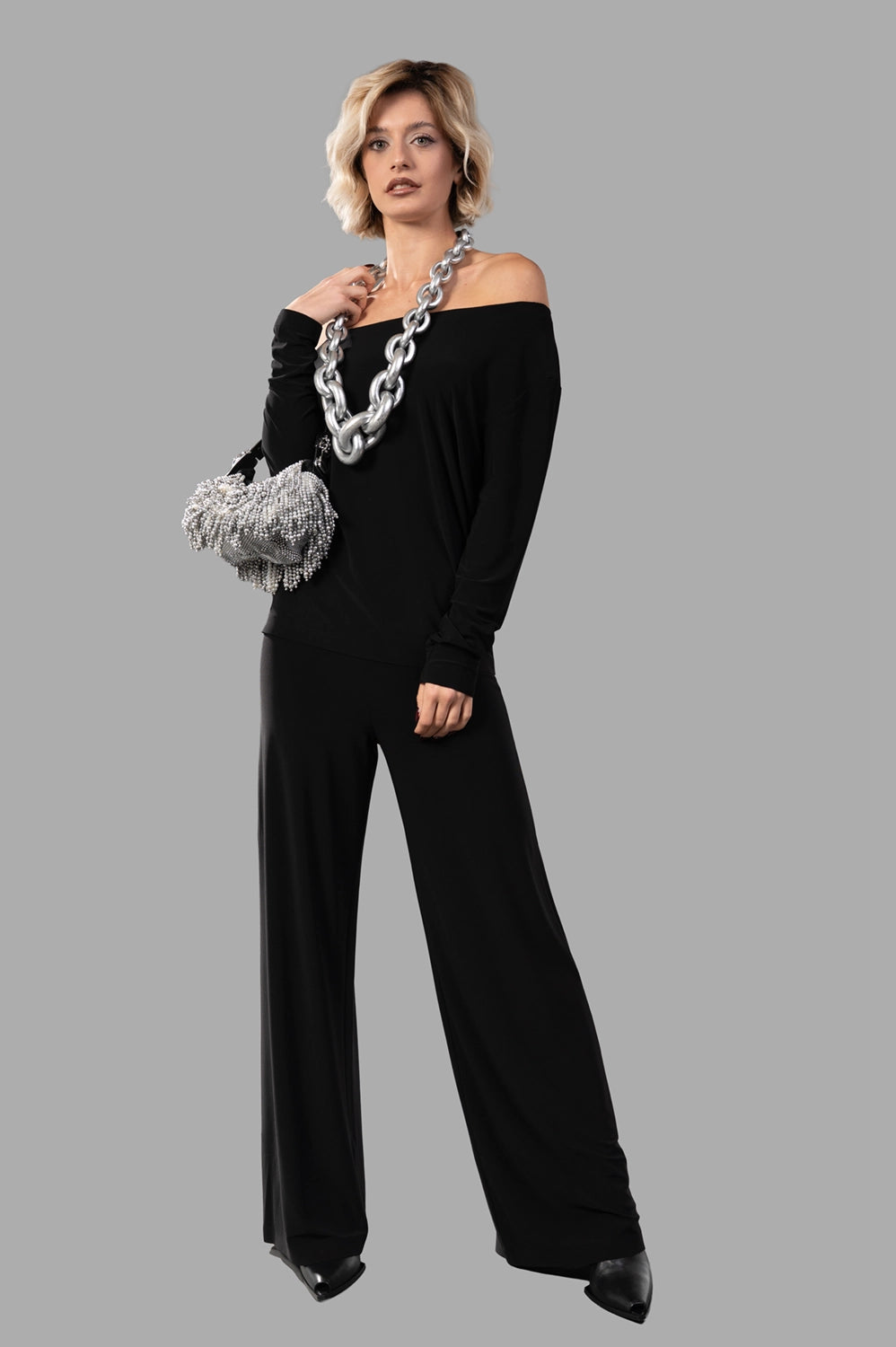 Norma Kamali top in black, on‑model full length, drop‑shoulder fit with hip‑length silhouette