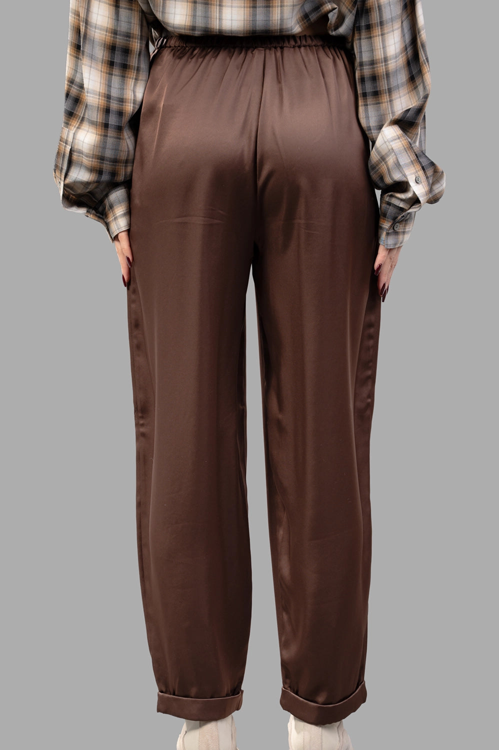 Back close-up of brown satin trousers showing elastic back waist and cuffed hem