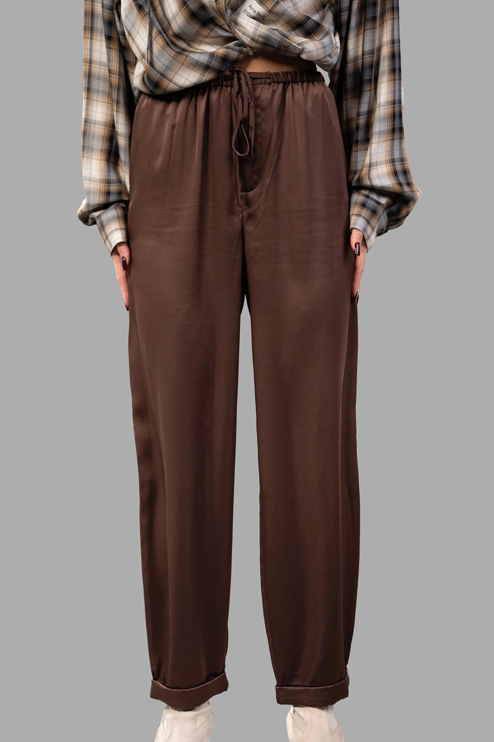 Front close-up of brown satin trousers with drawstring waist, zip fly and smooth finish