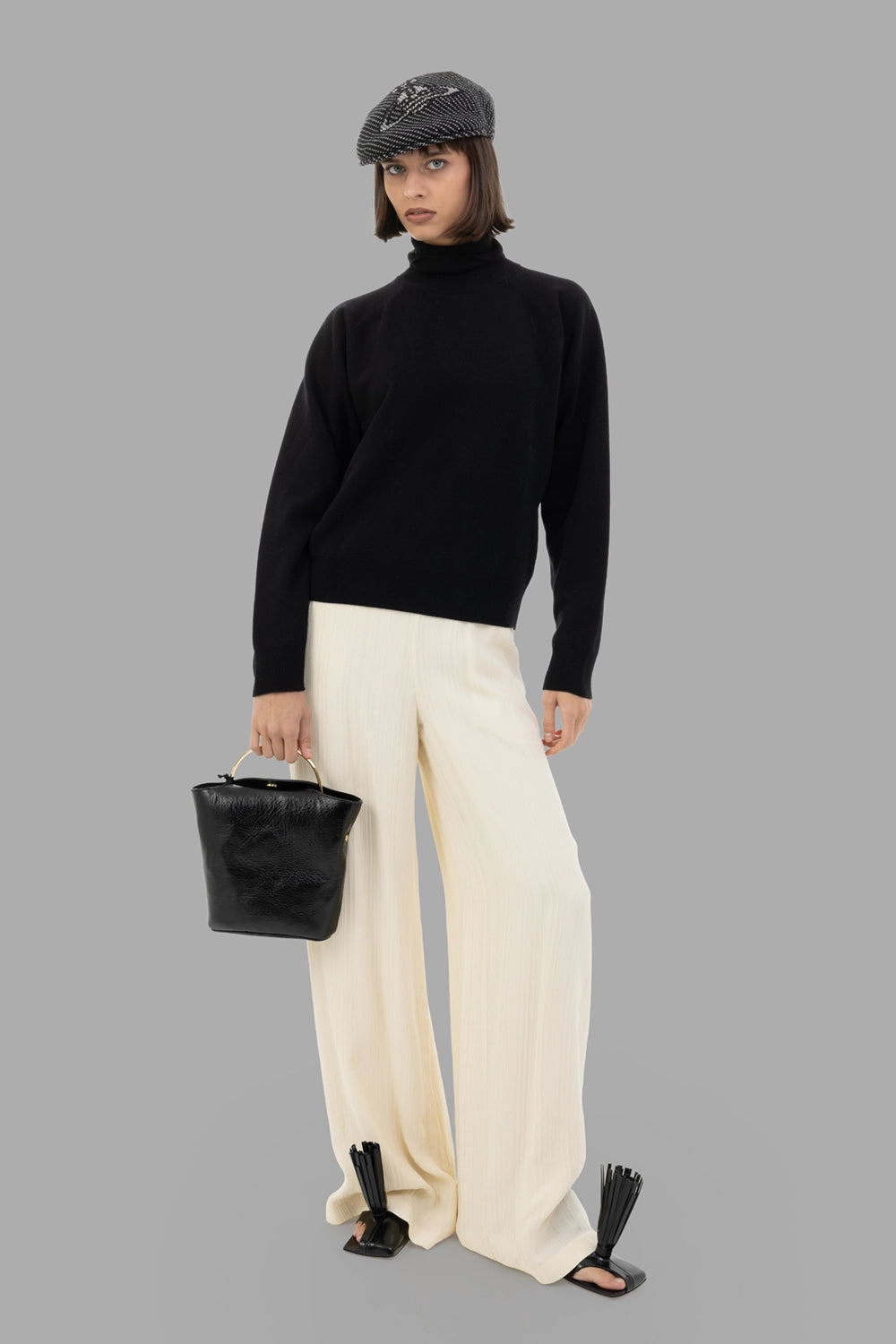 GentryPortofino women's turtleneck sweater in Nero, full-length on model, raglan sleeves and ribbed cuffs.