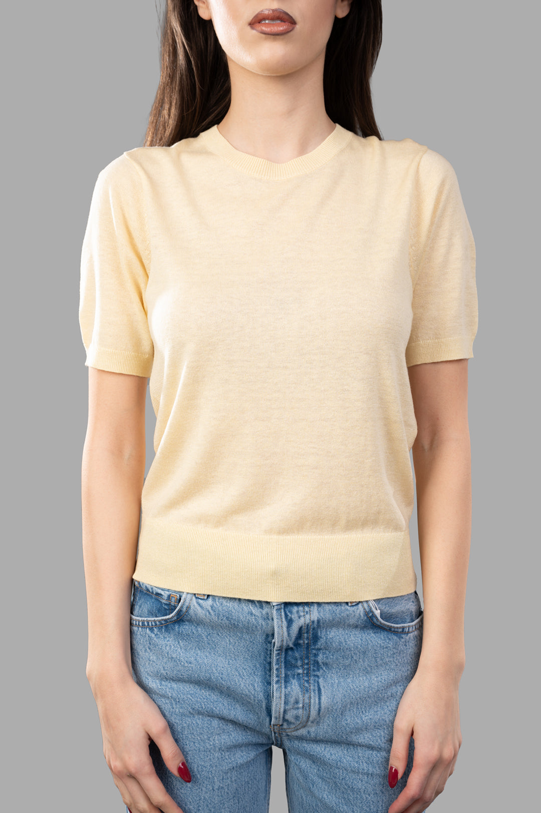 By Malene Birger Lelle Sweater in light yellow, featuring short sleeves, round neckline, and ribbed cuffs, worn with jeans.