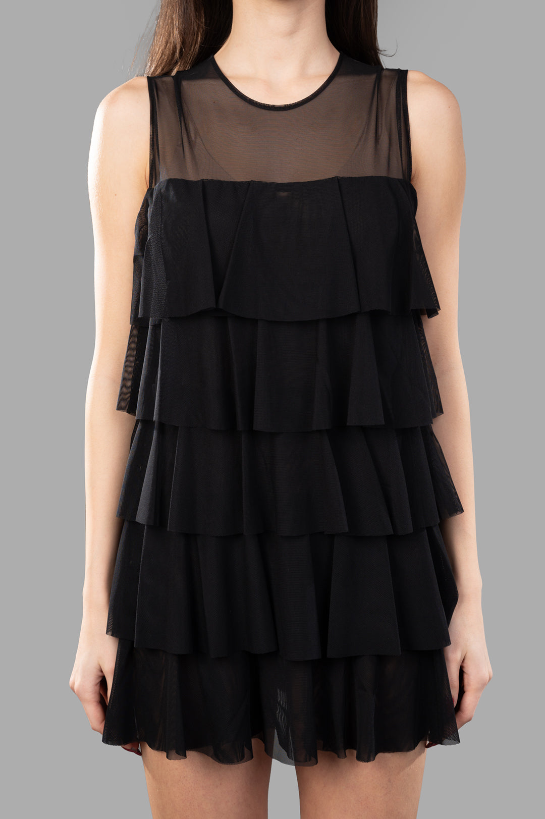 Norma Kamali Sleeveless Ruffle Dress showcases a slim fit with tiered ruffles, featured in a close-up view on the model.