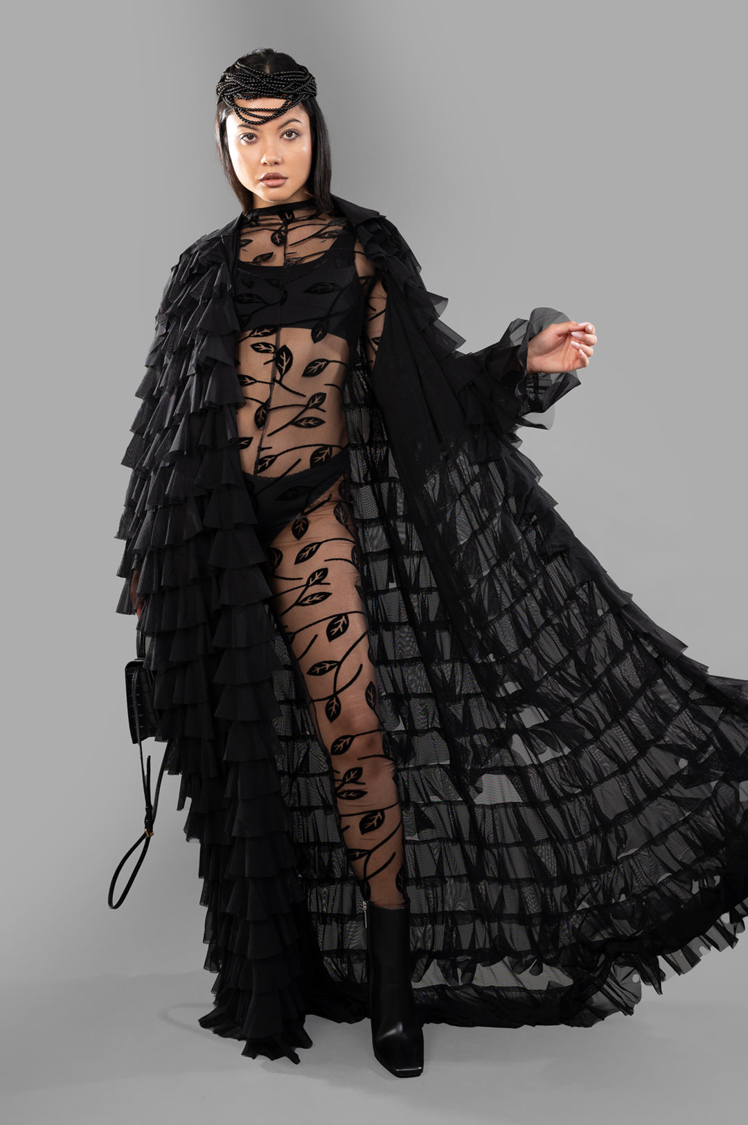 Norma Kamali All-over Ruffle Coat, front view on model, showcasing layered black ruffles and sheer design.
