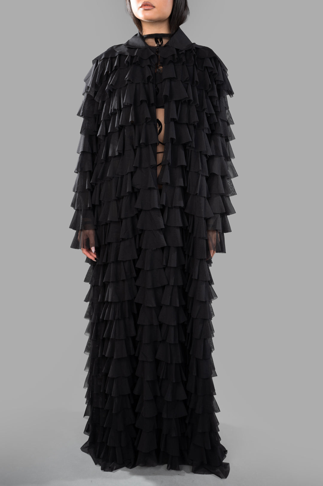 Norma Kamali All-over Ruffle Coat on model, showcasing intricate black ruffles, front view with collar detail.