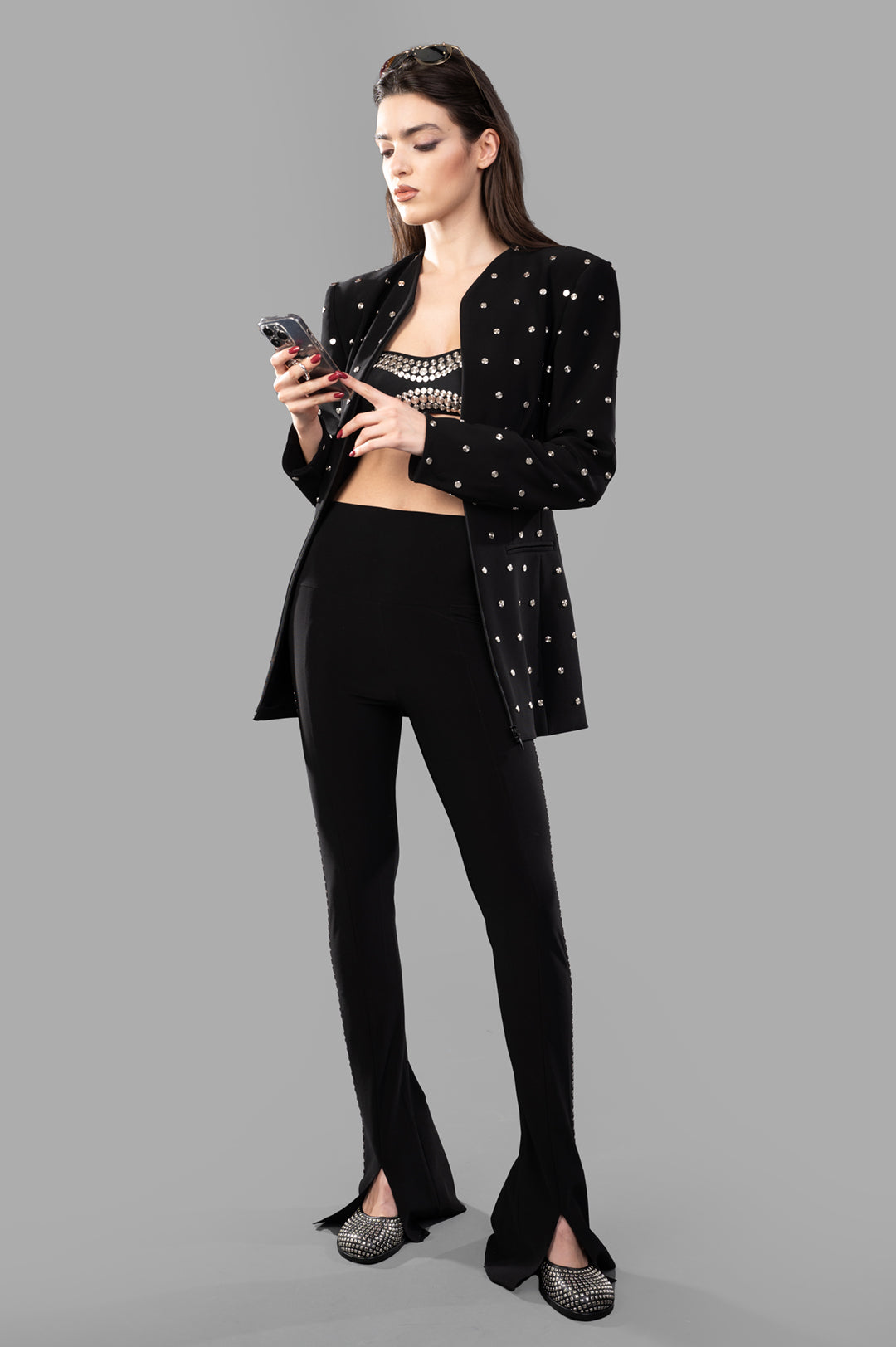 Norma Kamali Shoulder Pad Studded Jacket in black, front view on model, showing sleek fit and stud embellishments.