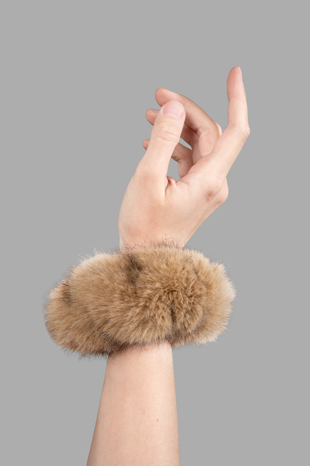 Close-up of tan faux-fur cuff showing dense pile, circular shape, and soft texture